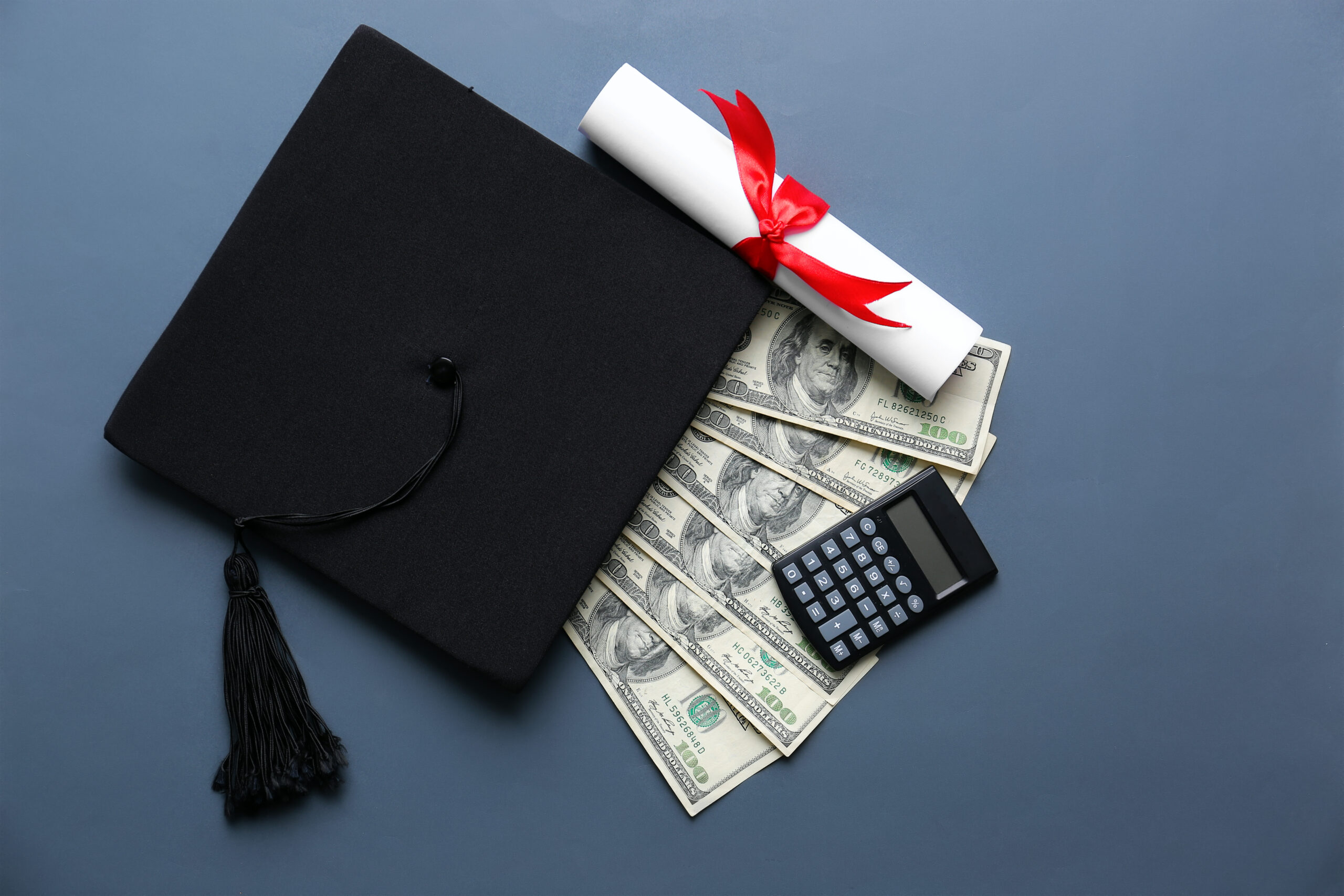 Mortar,Board,With,Diploma,Money,And,Calculator,On,Grey,Background.
