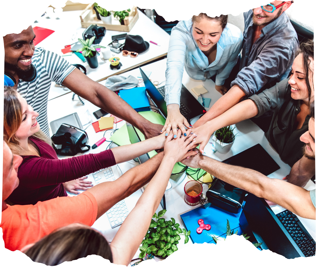Diverse team of professionals joining hands in a show of unity and collaboration around a colorful, modern workspace.